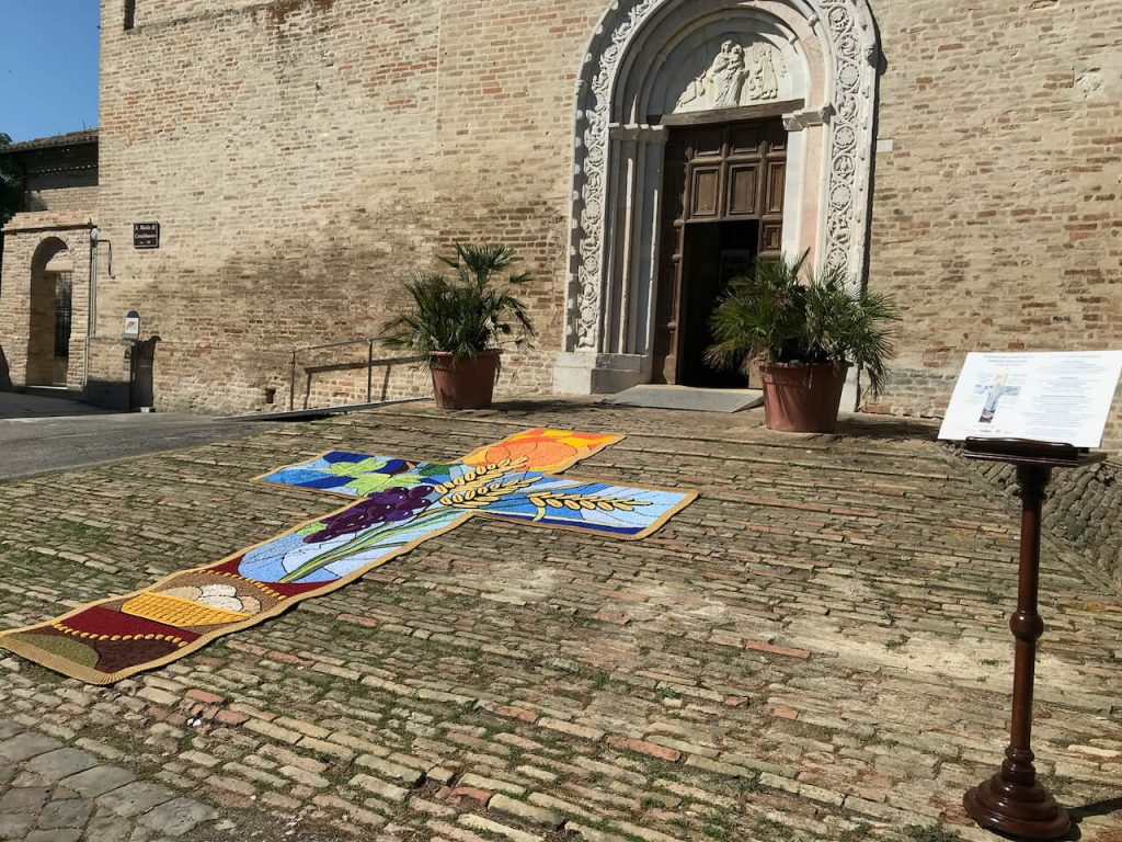 Recanati, il rione Castelnuovo brilla con la prima Infiorata all’uncinetto: il tappeto “Luce del Mondo” incanta i fedeli