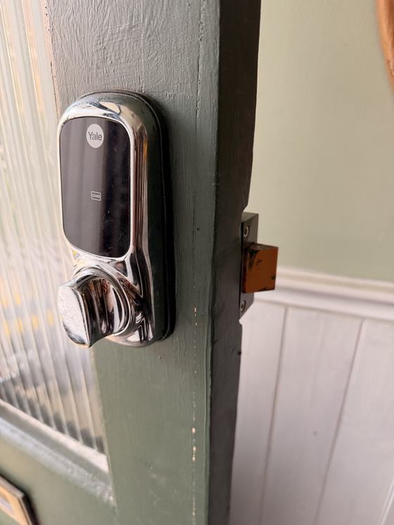 The inside face of the original Yale keypad lock, fitted high on a timber door immediately below the reeded glazing.