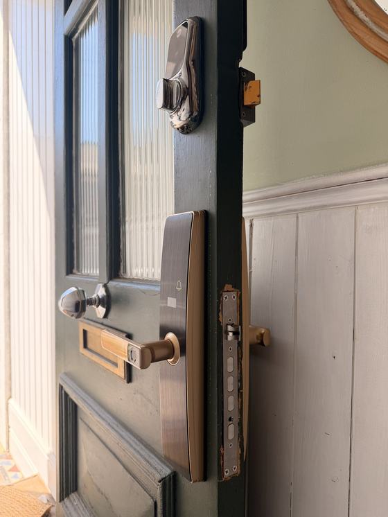 The finished door seen from inside: the original Yale nightlatch above, the new smart lock below it, and the lock body visible in the freshly cut door edge.